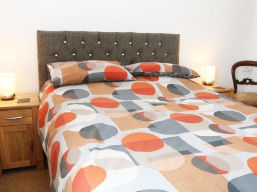 a bed with a colorful comforter and two pillows at Dalar Deg in Rhiw