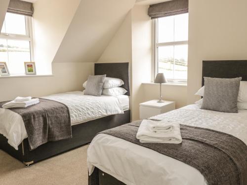 a bedroom with two beds and two windows at Bonjedward Mill Farm Cottage in Jedburgh