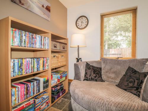 a living room with a couch and book shelves filled with dvds at Dolce Casa in Grantown on Spey