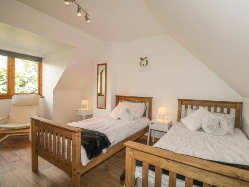 a bedroom with two beds and a chair and a window at Dolce Casa in Grantown on Spey