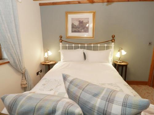 1 dormitorio con 1 cama blanca y 2 lámparas en Gelli Glud, en Eglwys-Fâch
