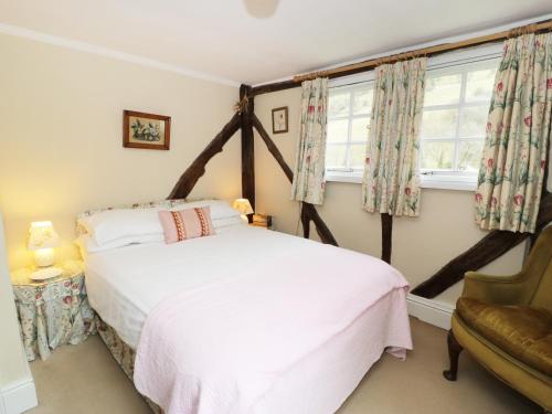 um quarto com uma cama, uma cadeira e uma janela em Dolgenau Hir - The Barn em Trefeglwys