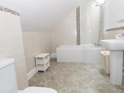 Un baño blanco con bañera y lavabo. en Westpoint, en Llandudno