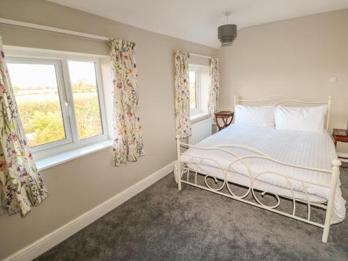 1 Schlafzimmer mit einem weißen Bett und 2 Fenstern in der Unterkunft 27 Whitegates in Great Yarmouth