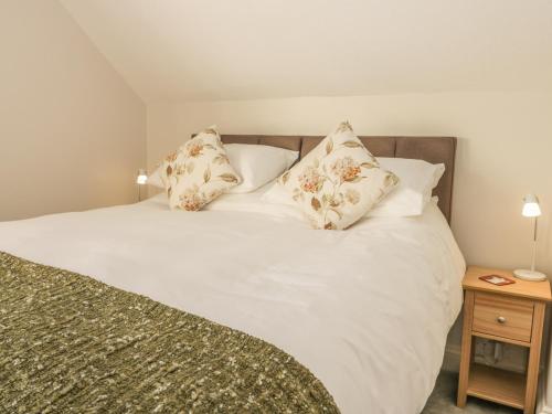 ein Bett mit weißer Bettwäsche und Kissen darauf in der Unterkunft Yew Court Cottage in Scarborough
