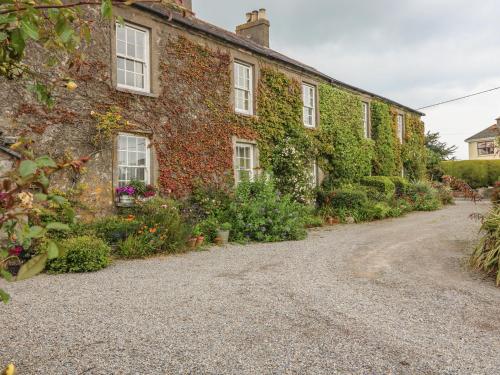 an ivy covered building with a gravel driveway at Cairbre House in Dungarvan