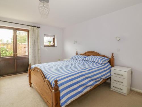 a bedroom with a bed with blue and white stripes at Lowbrook Cottage in Diss