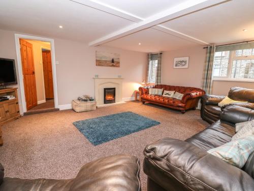 a living room with leather furniture and a fireplace at Fisher Granary in Lampeter