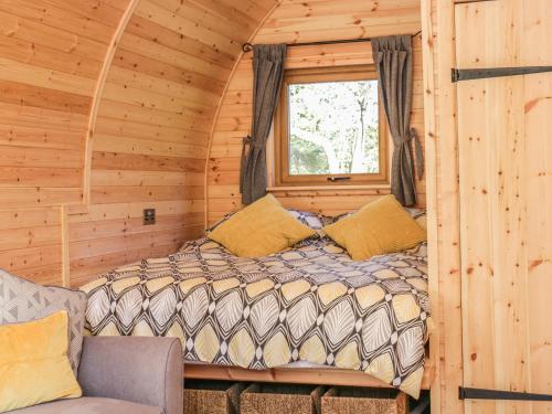 a bed in a log cabin with a window at Dingle Den in Hereford