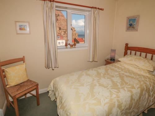 ein Schlafzimmer mit einem Bett, einem Stuhl und einem Fenster in der Unterkunft Fishermans Cottage in Saltburn-by-the-Sea