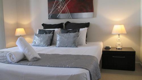 a bedroom with a large white bed with pillows at Edge Apartments Cairns in Cairns
