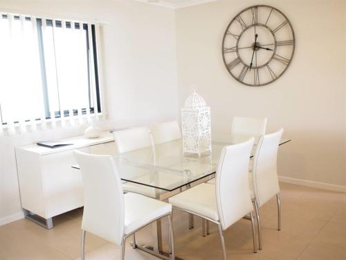 a dining room with a glass table and white chairs at Edge Apartments Cairns in Cairns