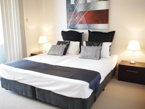 a large bed in a room with two lamps at Edge Apartments Cairns in Cairns