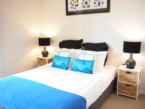 a bedroom with a bed with blue and white pillows at Edge Apartments Cairns in Cairns