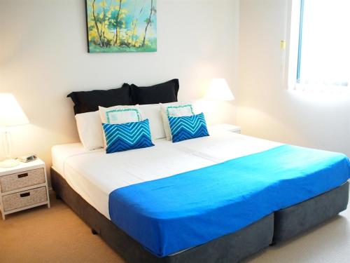 a bedroom with a large bed with blue and white pillows at Edge Apartments Cairns in Cairns