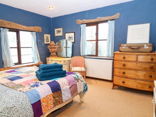 a bedroom with blue walls and a bed and a dresser at Spring Park Farmhouse in Launceston