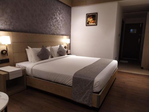 a bedroom with a large bed with white sheets and pillows at MothiMahal Residency Thrissur in Trichūr
