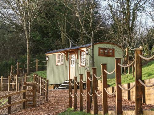 a small green building with a wooden fence at Little Silver Leaf in High Bickington