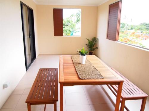 a wooden table and two benches in a room at Edge Apartments Cairns in Cairns