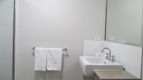 a white bathroom with a sink and a mirror at Edge Apartments Cairns in Cairns