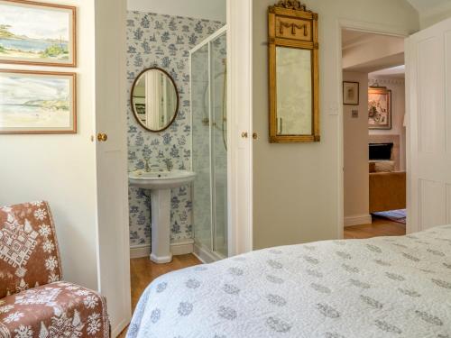 a bedroom with a bathroom with a sink and a mirror at All Souls Cottage in Cirencester