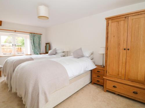 a bedroom with a large white bed and a wooden cabinet at Greenham Cottage in Chiselborough