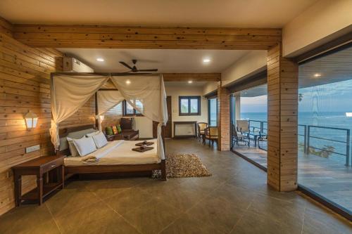 a bedroom with a bed and a view of the ocean at SaffronStays Athaang, Dapoli in Ānjarle