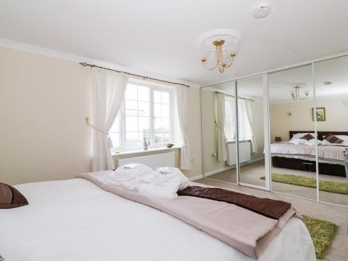 ein Schlafzimmer mit einem großen weißen Bett und einem Spiegel in der Unterkunft The Duck House in Norwich