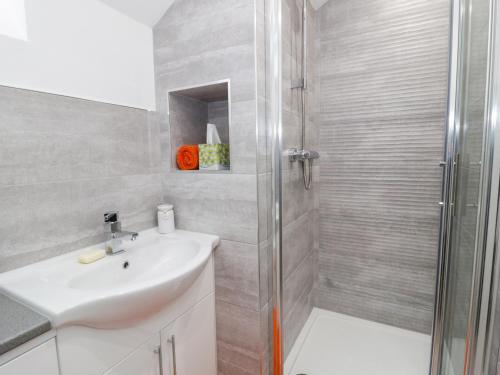 a white bathroom with a shower and a sink at Bwlch Y Gwynt Bach in Llangefni