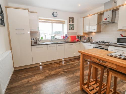 a kitchen with white cabinets and a wooden table at Tides Reach in Rhosneigr