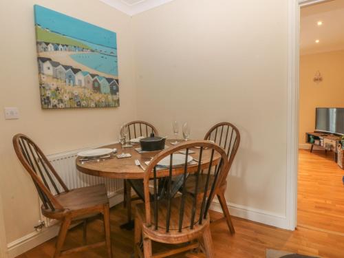 a dining room table with chairs and a painting on the wall at Tides Reach in Rhosneigr
