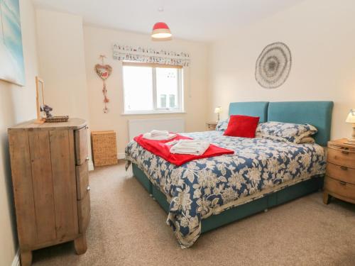 a bedroom with a bed and a dresser and a window at Tides Reach in Rhosneigr