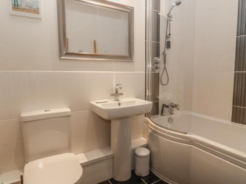 a bathroom with a sink and a toilet and a shower at Tides Reach in Rhosneigr
