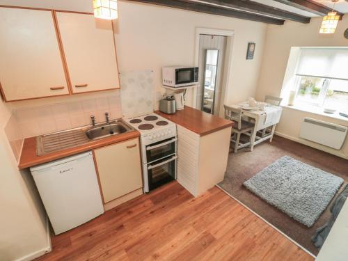 a kitchen with a sink and a stove top oven at Wren Cottage in Morpeth