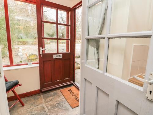 an open door with a window and a chair at Wren Cottage in Morpeth