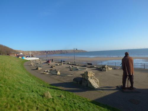 a man standing on a sidewalk near the beach at Sailors Lodge in Filey
