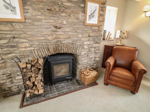 a living room with a stone fireplace and a chair at The Old Stables in Minehead