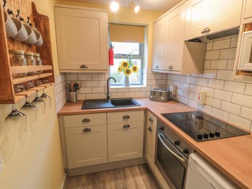 a kitchen with white cabinets and a sink and a window at Fauna's Corner in Whitby