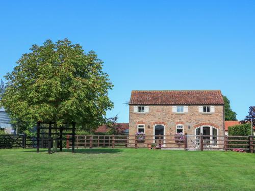 a large brick house with a tree in the yard at Owl's Roost in Alford