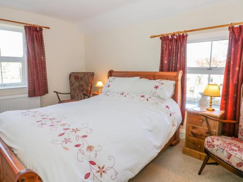 Un dormitorio con una cama con una colcha blanca con flores. en Dove Cottage en Whitby