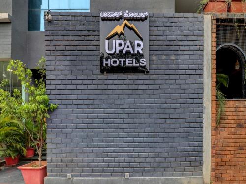 um sinal para um hotel numa parede de tijolos em Upar Hotels Indiranagar em Bangalore