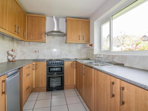 a kitchen with wooden cabinets and a stove and a window at Brambles in Gorran Haven