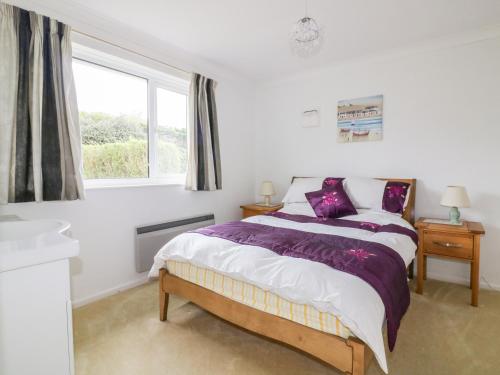 een witte slaapkamer met een bed en een raam bij Brambles in Gorran Haven