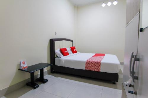 una camera da letto con un letto con cuscini rossi e un tavolo di OYO 3334 Ratu Residence a Medan