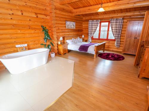 a log cabin bathroom with a bed and a tub at Beech Lodge in Oakham