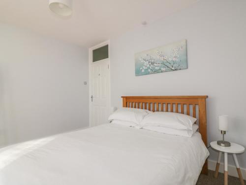 a white bedroom with a bed and a picture on the wall at Chy-an-Brae in Newquay