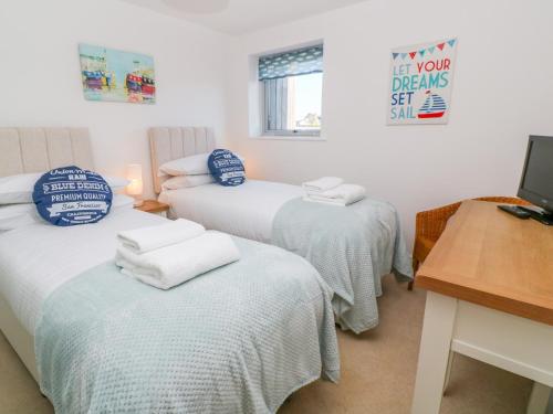 - une chambre avec 3 lits et des serviettes dans l'établissement Ocean Seven, à Newquay