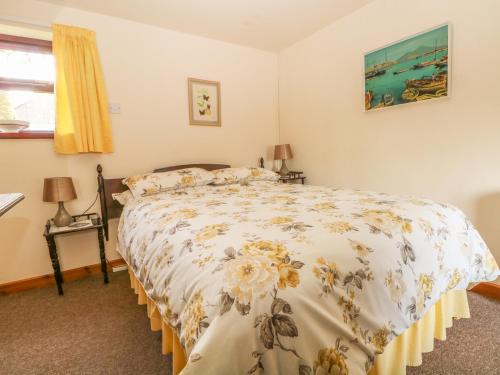 a bedroom with a bed with a floral bedspread at Cordwainer Cottage in Stoke on Trent