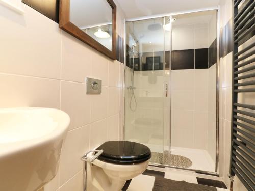 a bathroom with a toilet with a glass shower at The Cart House in Liskeard