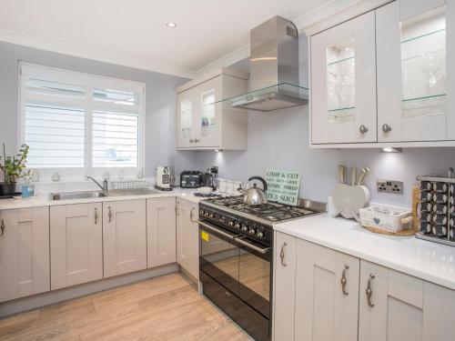 a kitchen with white cabinets and a stove top oven at Gadlys in Trearddur
